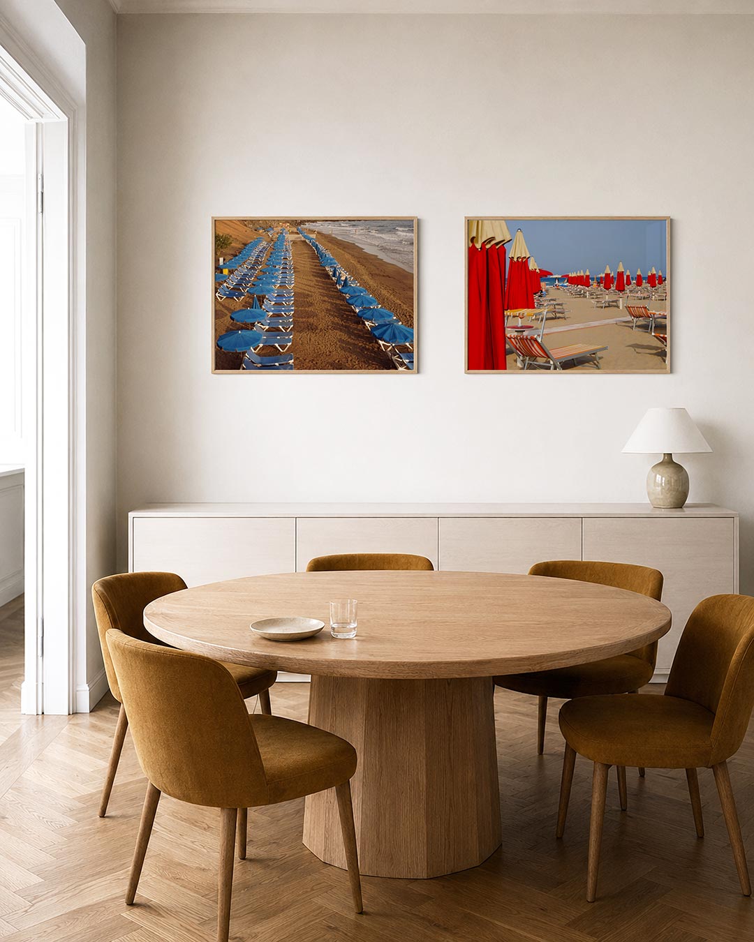 Interieurbeeld met twee liggende posters: een ritmische ordening van blauwe parasols en ligbedden op een zandstrand