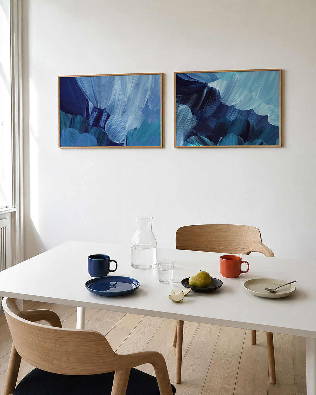Tweedelige posterset met vloeiende blauwe penseelstreken die elkaar overlappen, getoond in een interieur