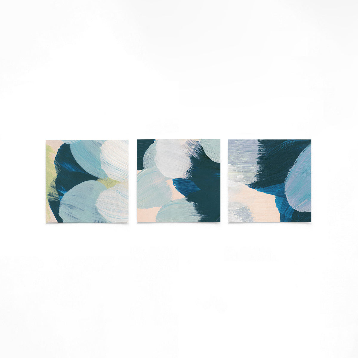 Drie vierkante posters met abstracte blauwe vormen op een gebroken witte achtergrond