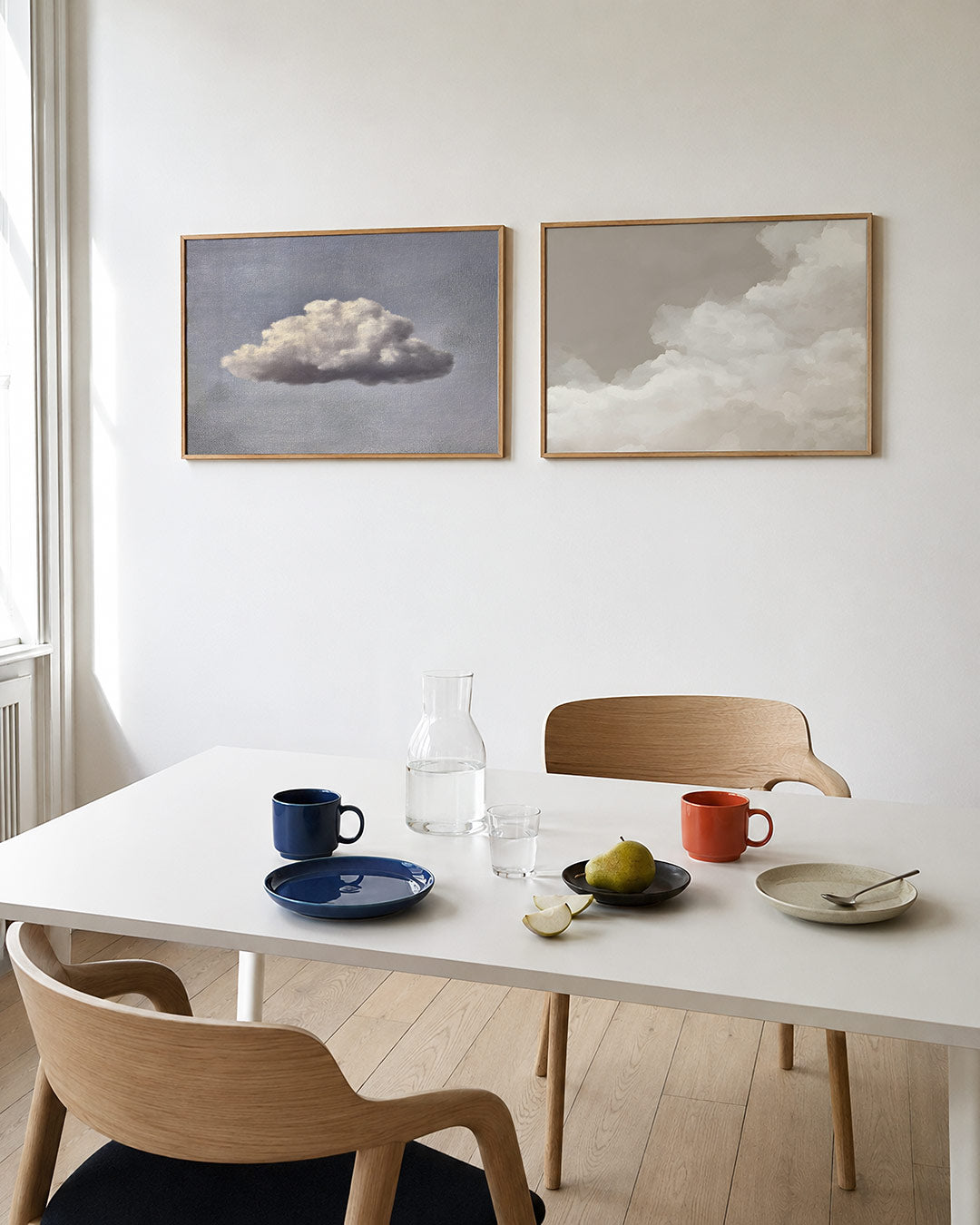 Twee liggende posters met een zachte witte wolk in een fijne, blauwgrijze lucht, aan de muur in een interieur