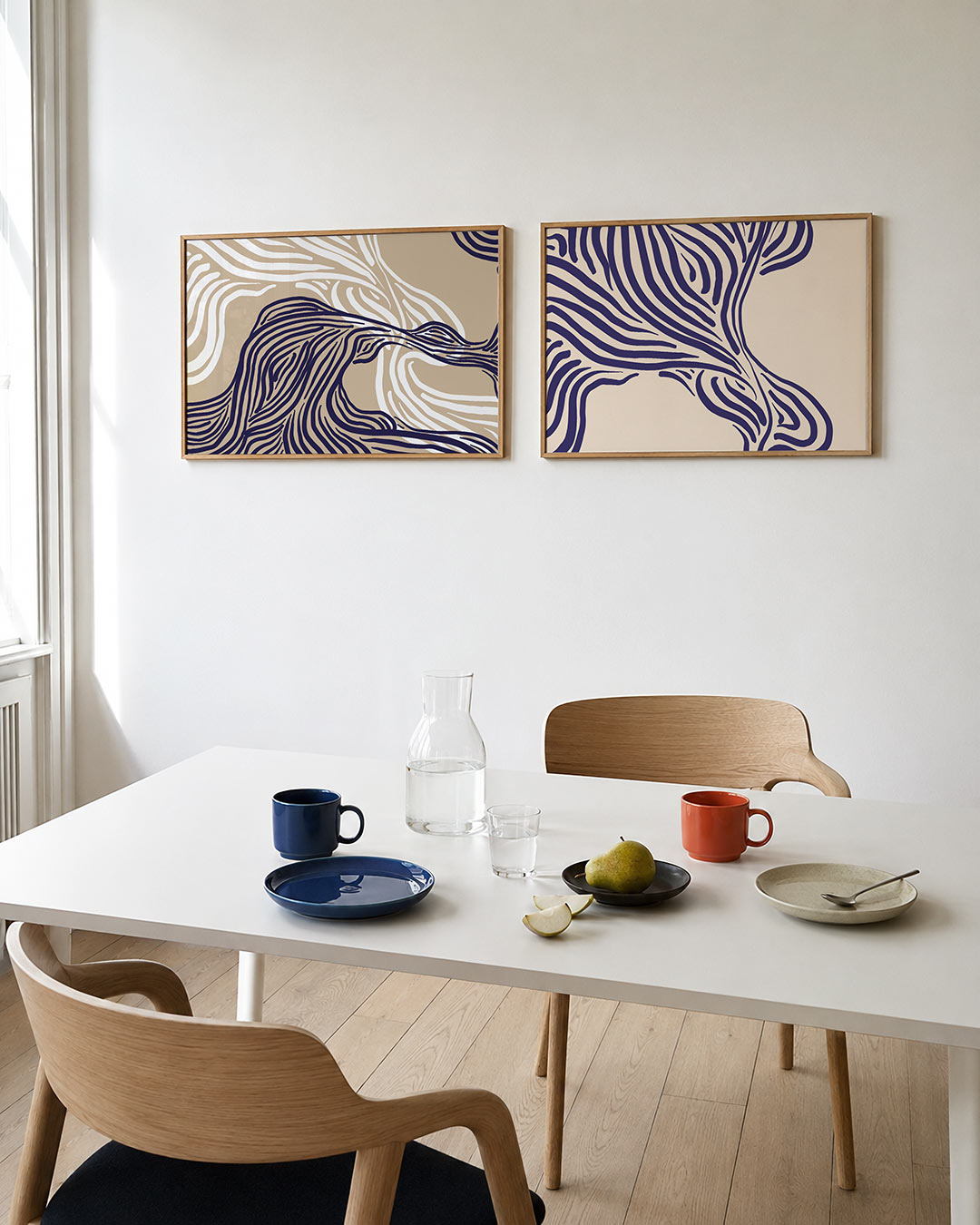 Tweedelige posterset met vloeiende, golvende lijnen in donkerblauw en wit op een beige achtergrond, getoond in een interieur
