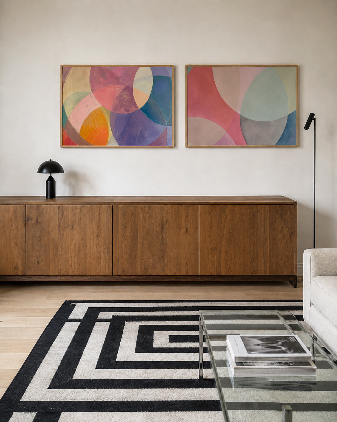 Twee liggende posters met overlappende cirkels in zachte tinten roze, paars, geel en blauw, aan de muur in een interieur