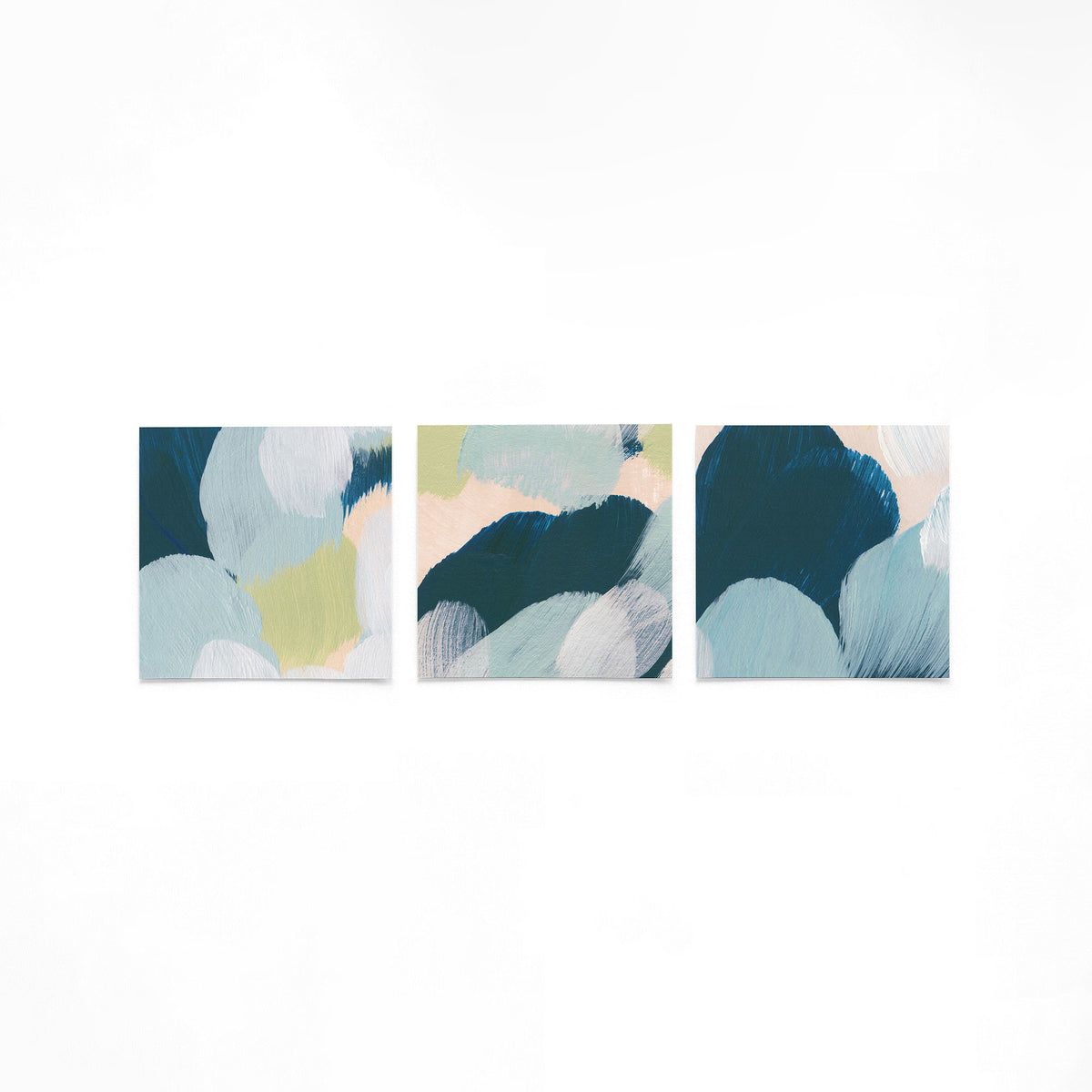 Drie vierkante posters met abstracte blauwe penseelstreken op een gebroken witte achtergrond