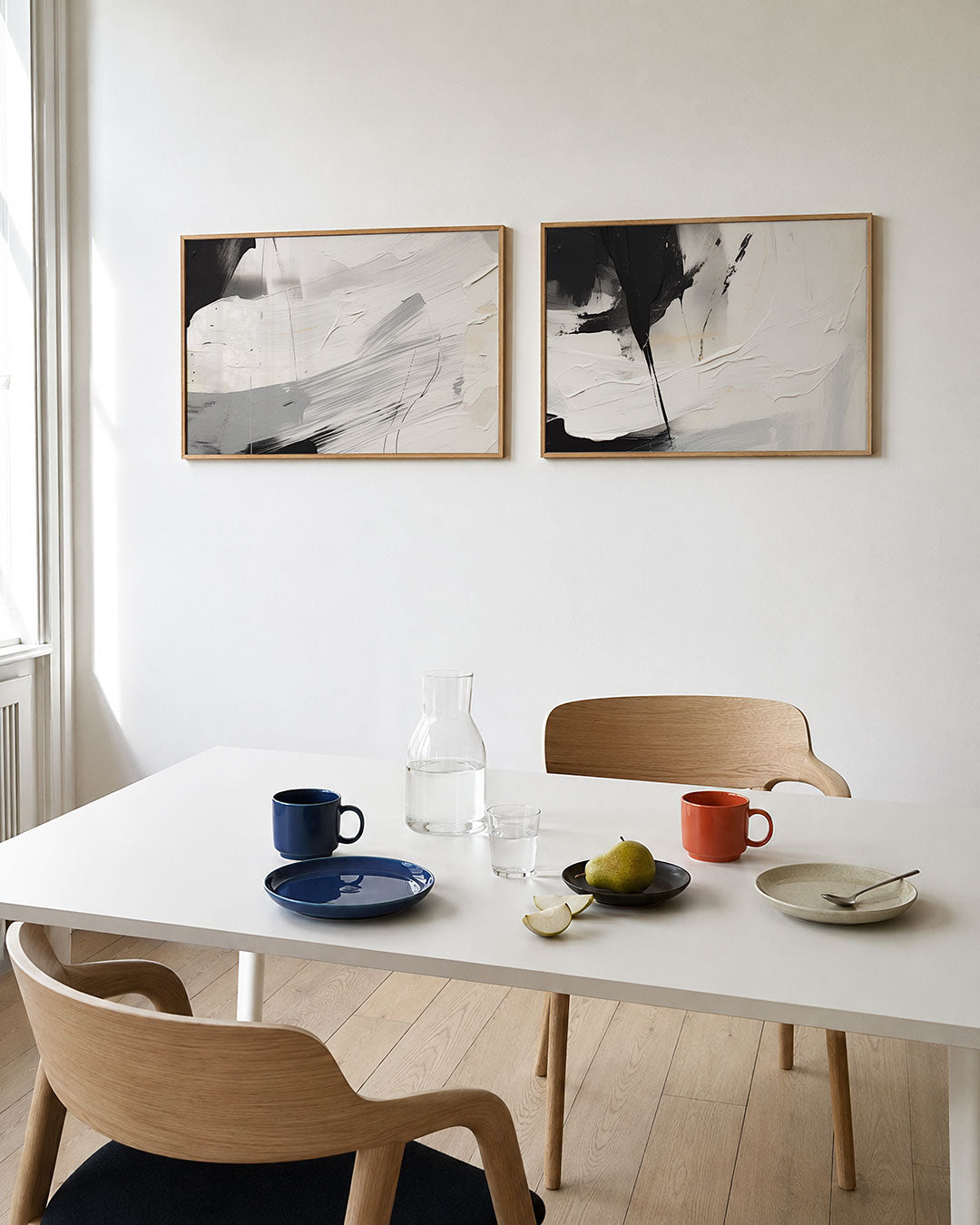 Twee liggende posters met krachtige penseelstreken in zwart, wit en grijs, aan de muur in een interieur