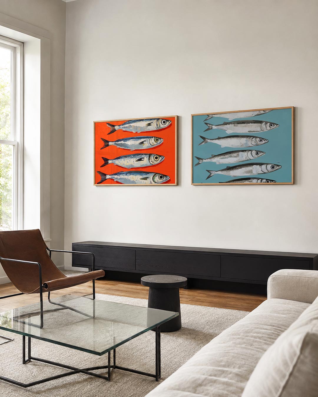 Twee liggende posters met vier vissen in blauw- en grijstinten op een oranje achtergrond, aan de muur in een interieur