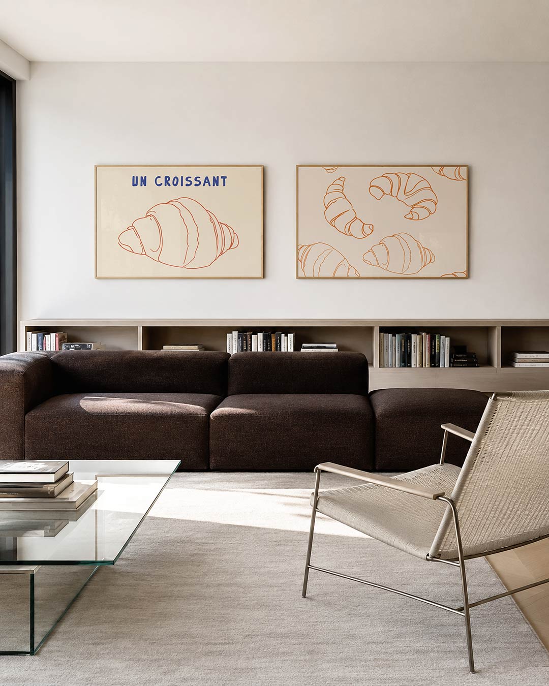 Twee liggende posters met een oranje lijntekening van een croissant en de blauwe tekst ‘UN, aan de muur in een interieur