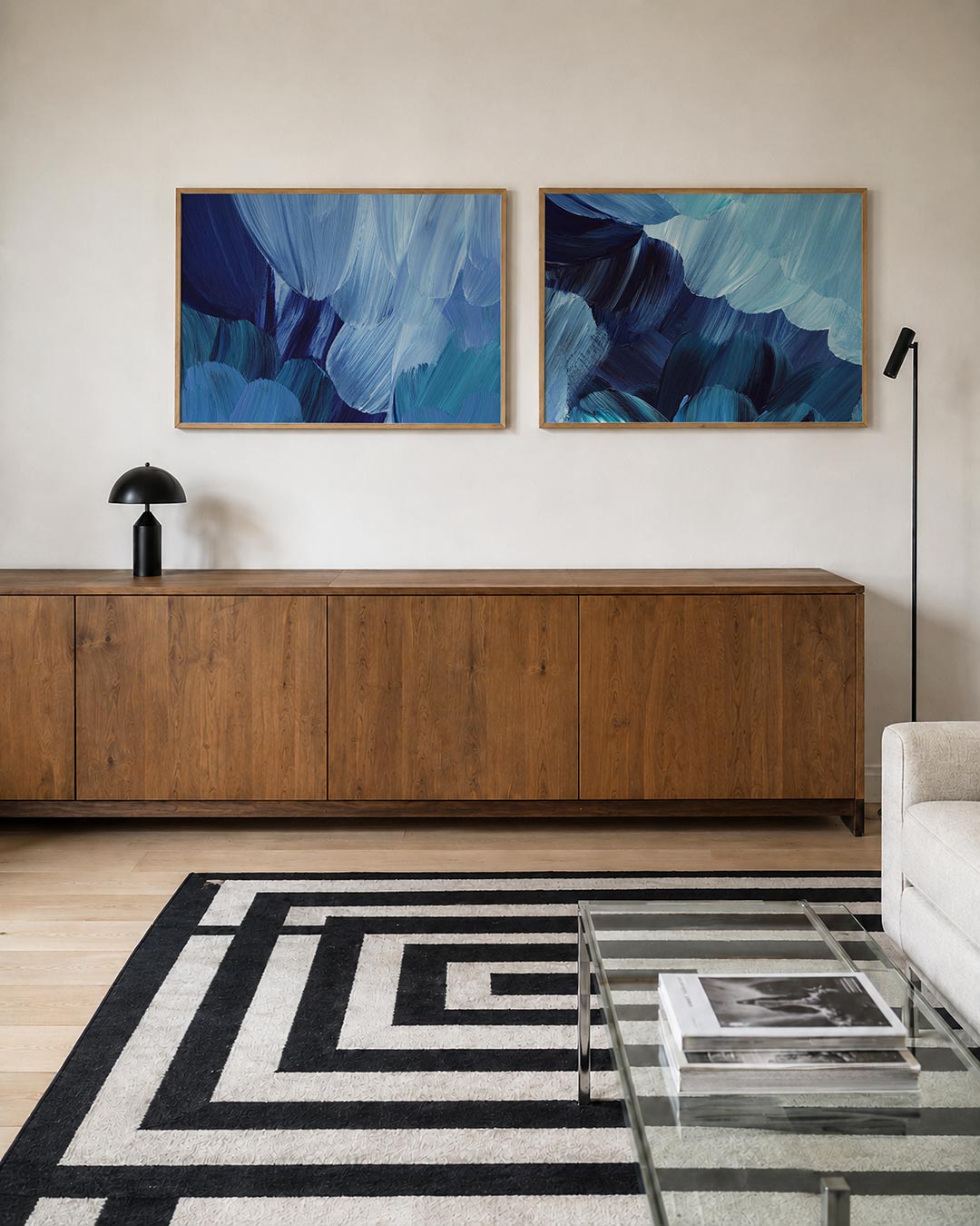 Twee liggende posters met vloeiende blauwe penseelstreken die elkaar overlappen, aan de muur in een interieur