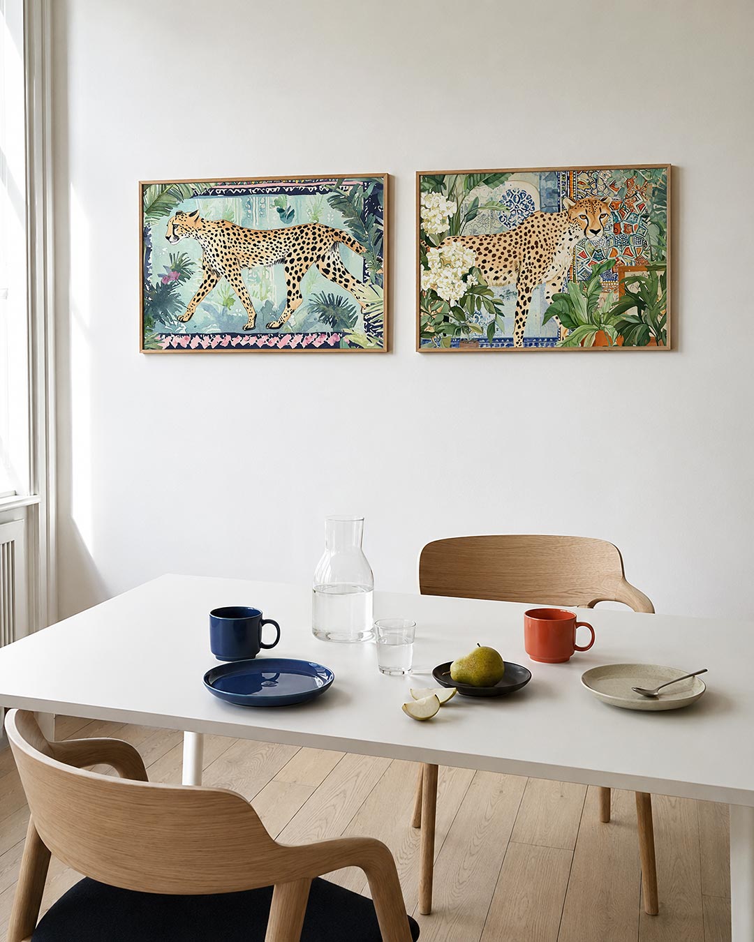 Twee liggende posters met een sierlijke cheetah in een weelderig groen landschap, aan de muur in een interieur