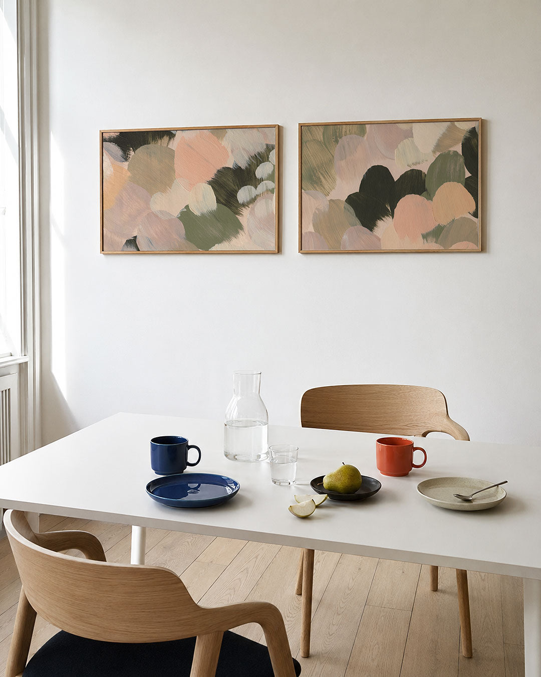 Twee liggende posters met zachte, ronde kleurvlakken in pastelkleuren, aan de muur in een interieur